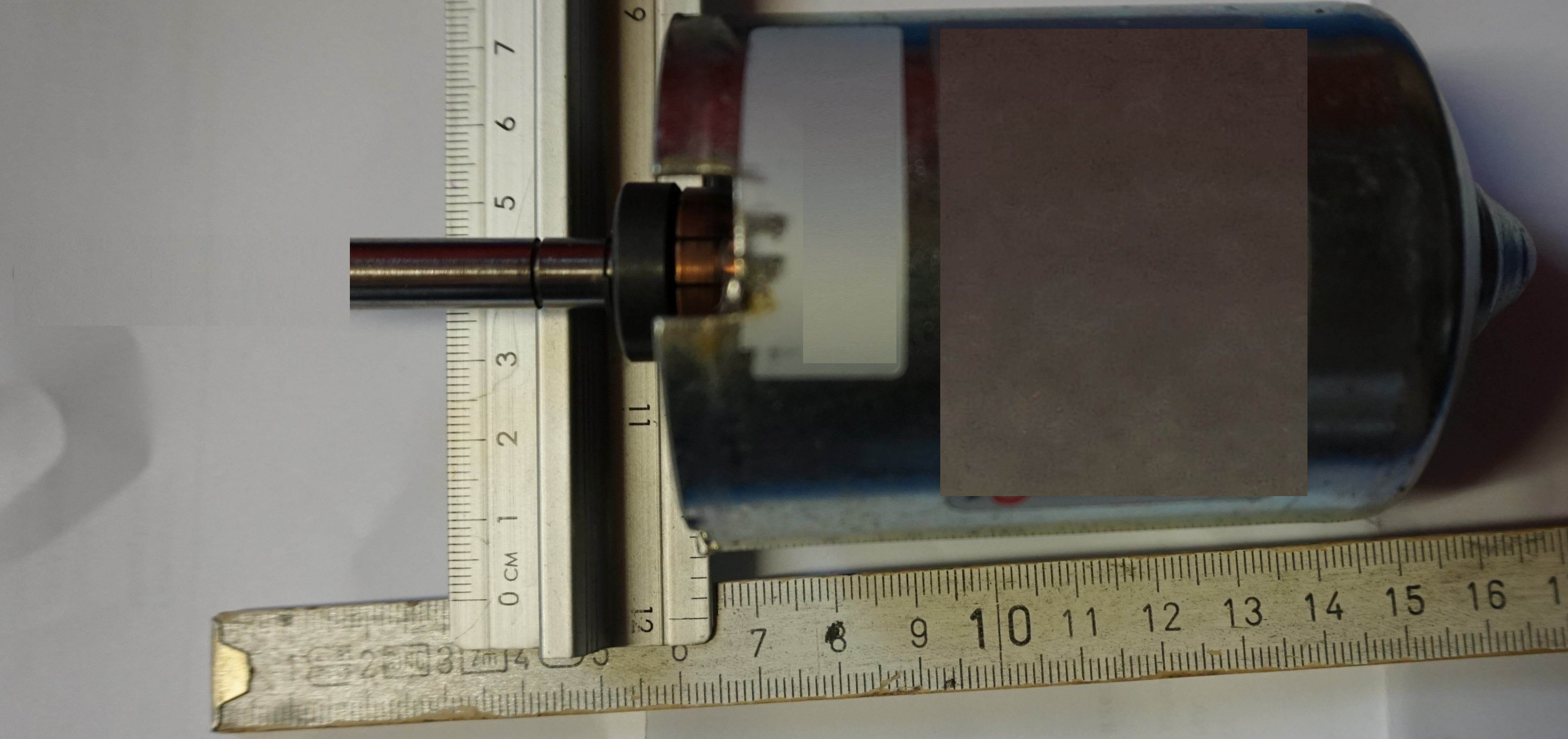 Elektromotor-Glossar-Blog, Tachogenerator ein kleiner Geno, vorgesehen f&uuml;r die Drehzahlr&uuml;ckf&uuml;hrung beim gro&szlig;en DC Motor, die fr&uuml;heren Drehzahlregelungen., im Bild der Tahogenerator mit Zollstock l&auml;ngs und Zollstock quer ... zu sehen.